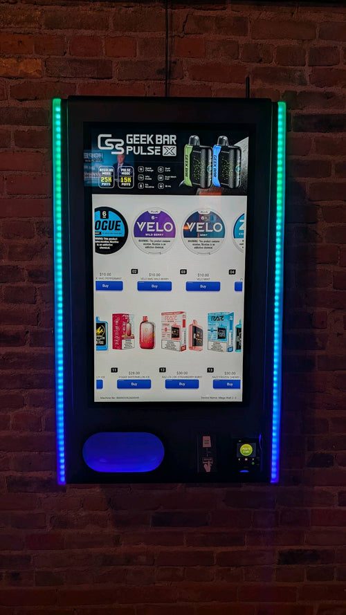 Vapor Vault vape vending machine mounted on an exposed brick wall with blue and green LED edge lighting